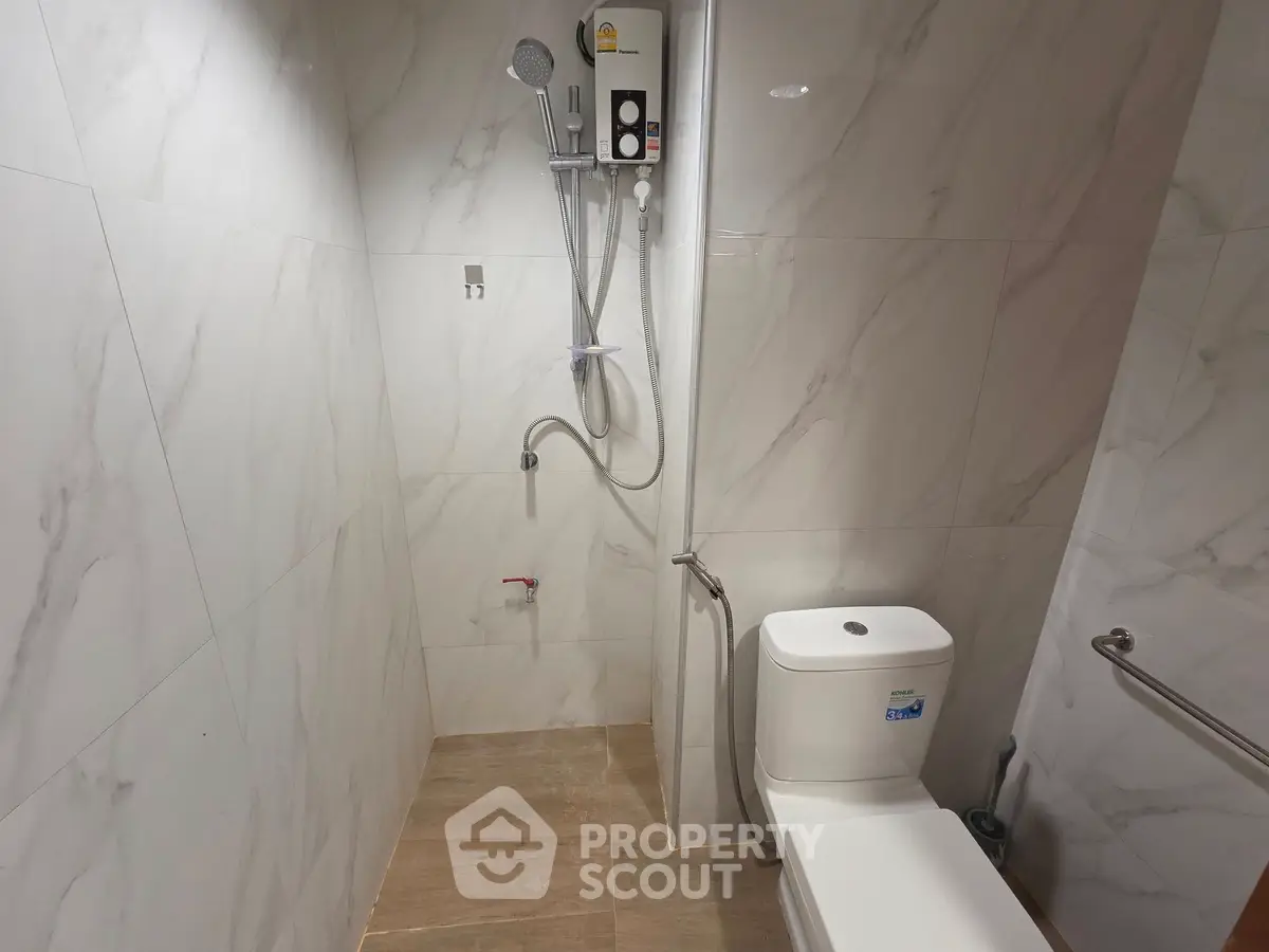 Modern bathroom with shower and toilet in sleek marble design.