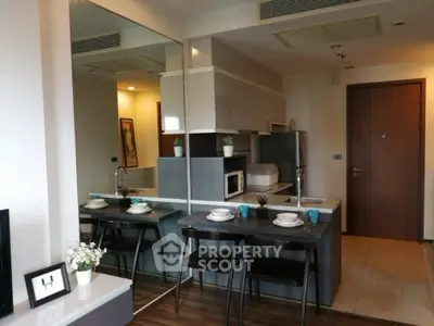 Modern kitchen with sleek design and dining area in compact apartment.