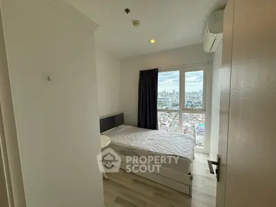 Modern bedroom with city view, featuring a cozy bed and large window for natural light.