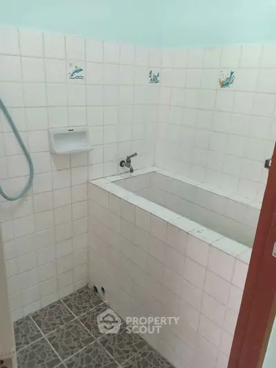 Compact bathroom with tiled walls and built-in bathtub, ideal for small spaces.