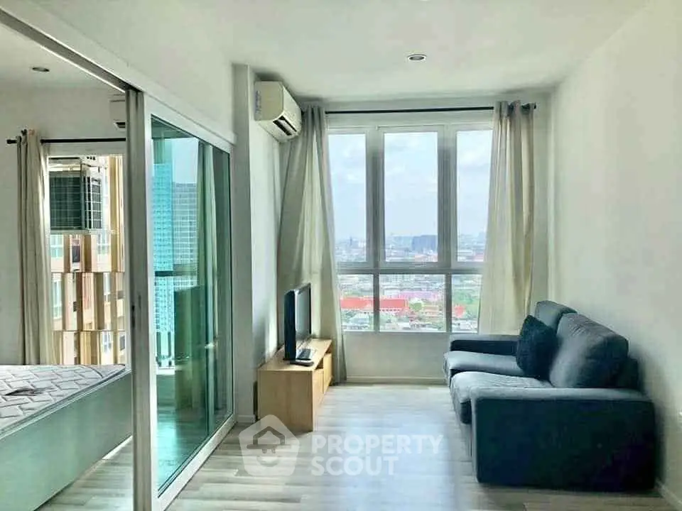 Bright living room with large windows and city view, featuring modern furniture and sleek flooring.