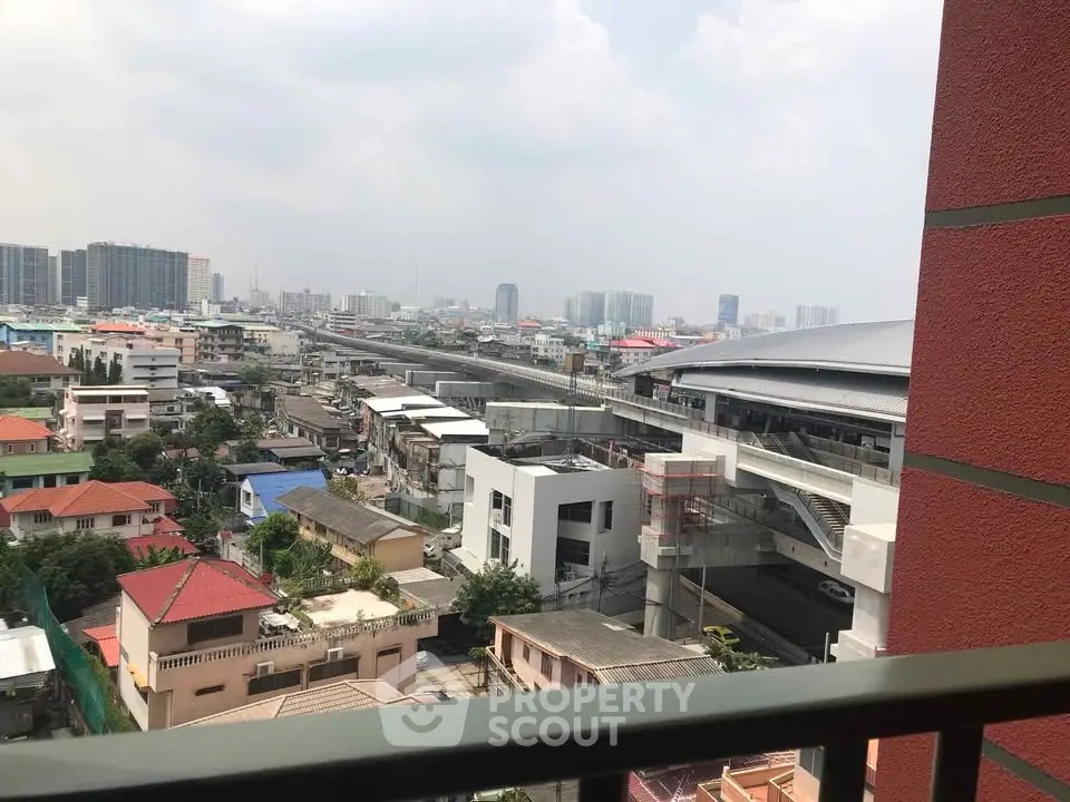 Stunning urban view from balcony overlooking cityscape and modern transit station.