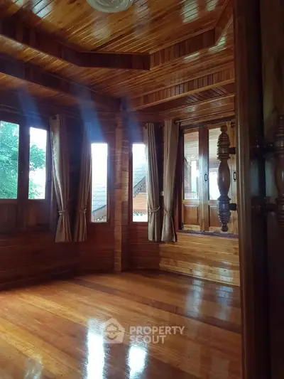 Stunning wooden interior with large windows and polished floors, perfect for a cozy living space.