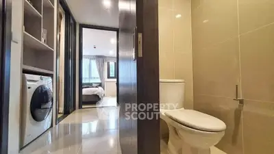 Modern apartment interior with bathroom and laundry area, featuring sleek design and natural lighting.