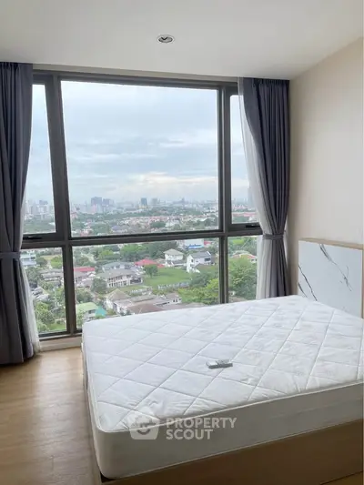 Spacious bedroom with large window offering stunning cityscape views.