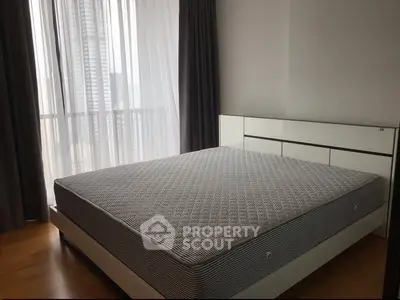 Modern bedroom with large window and stylish bed frame in high-rise apartment.
