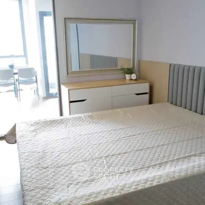 Modern bedroom with stylish decor and large mirror, featuring a cozy bed and natural light.