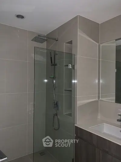 Modern bathroom with glass shower and sleek vanity in contemporary home.