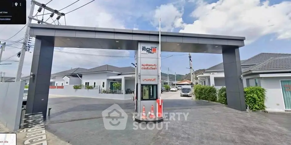 Modern gated community entrance with security booth and stylish archway.