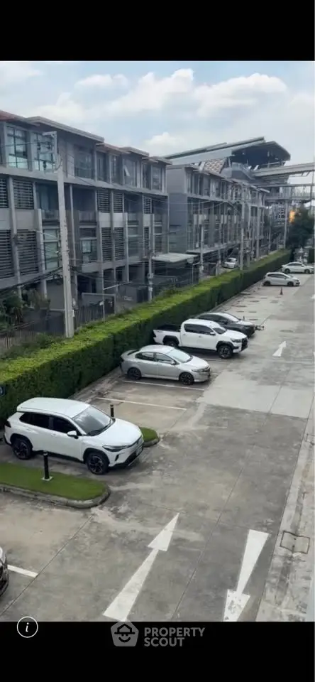Modern residential building with parking area and greenery, showcasing urban living convenience.