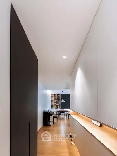 Sleek modern hallway leading to a stylish living area with wooden flooring and contemporary design.