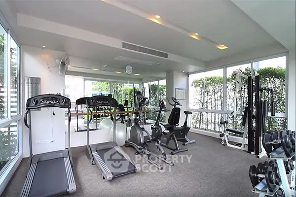 Modern gym with state-of-the-art equipment and large windows for natural light.