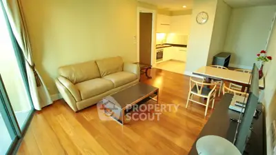 Spacious living room with wooden flooring and modern furniture in a cozy apartment.