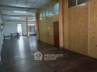 Spacious wooden interior with natural light and ceiling fan, ideal for versatile living space.