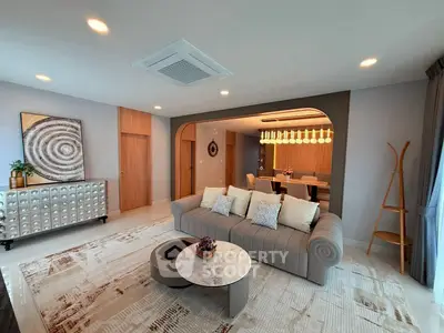 Elegant living room with modern decor and open dining area, featuring stylish furniture and ambient lighting.