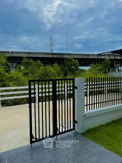 Modern gated entrance with scenic view of greenery and highway