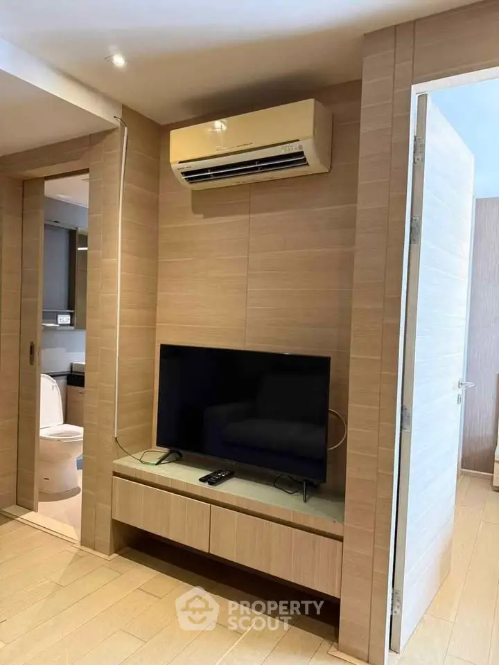 Modern living room with sleek TV setup and air conditioning, showcasing contemporary interior design.