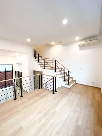 Spacious modern living room with wooden flooring and stylish staircase