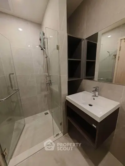 Modern bathroom with glass shower and sleek vanity in contemporary design.