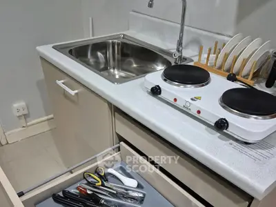 Compact kitchen with electric stove and dish rack, ideal for small spaces.