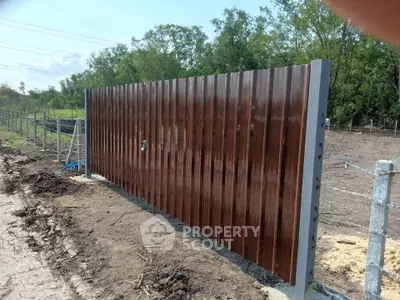 Modern metal gate with sleek design in a rural setting, perfect for secure property access.