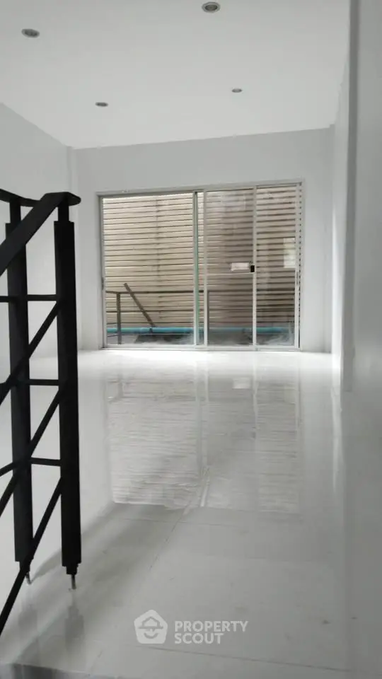 Spacious modern interior with sleek staircase and large sliding glass doors leading to a private outdoor area.
