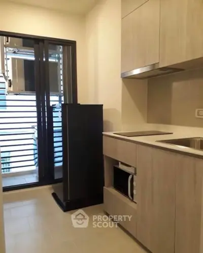 Modern kitchen with sleek cabinetry and built-in microwave in a compact layout.