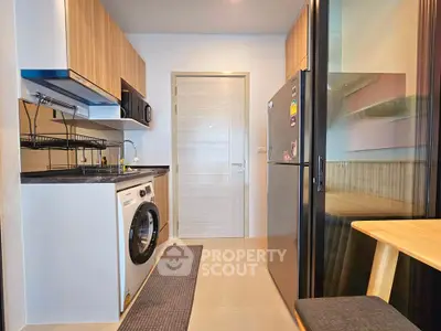 Modern kitchen with washing machine and sleek appliances in compact layout.