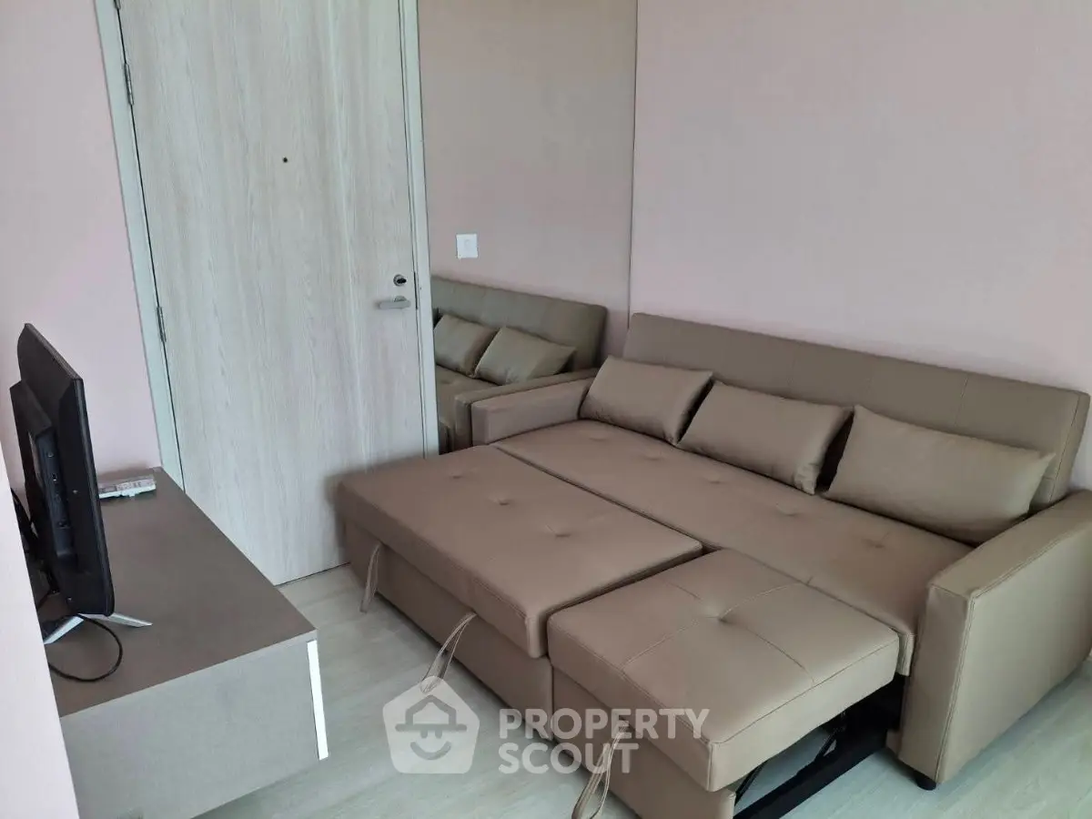 Modern living room with beige sofa bed and flat-screen TV, perfect for cozy relaxation.