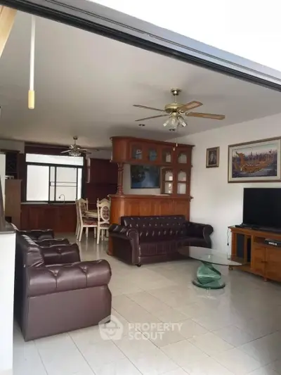 Spacious living room with elegant leather sofas and wooden cabinetry, perfect for family gatherings.