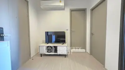 Modern minimalist living room with TV and air conditioning in a compact apartment.