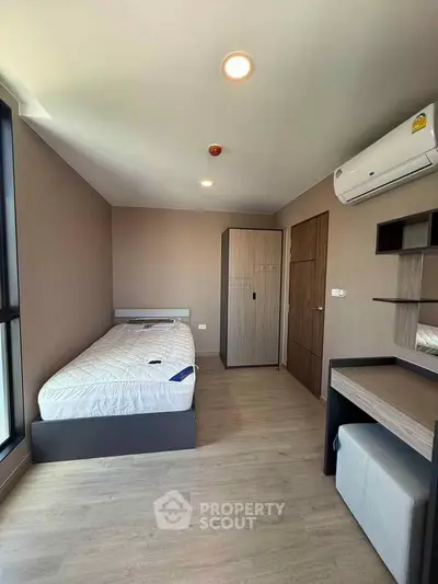 Modern bedroom with minimalist design, featuring a single bed, wardrobe, and air conditioning.