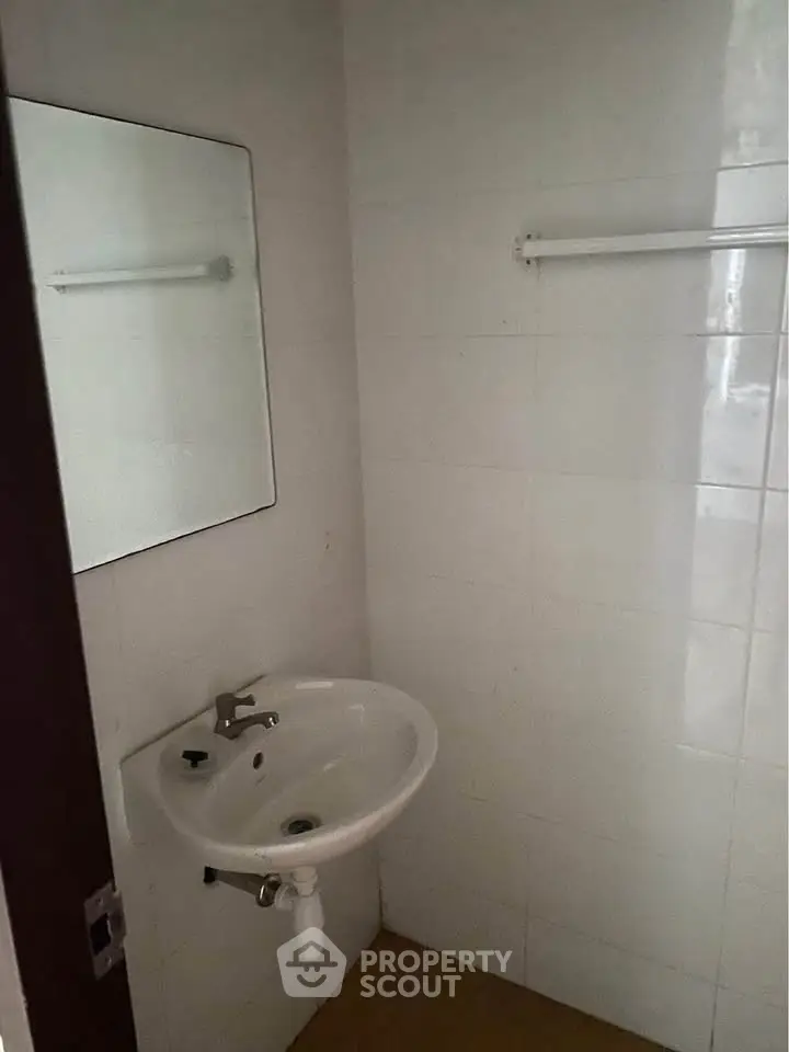 Compact bathroom with wall-mounted sink and mirror, ideal for small spaces.