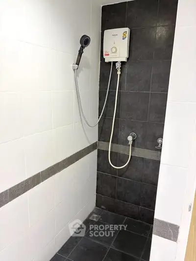 Modern bathroom with sleek black and white tiles and a wall-mounted shower heater.
