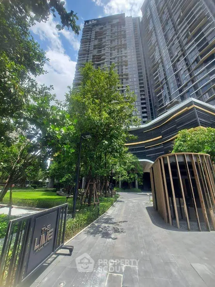 Modern high-rise building with lush garden and sleek entrance pathway
