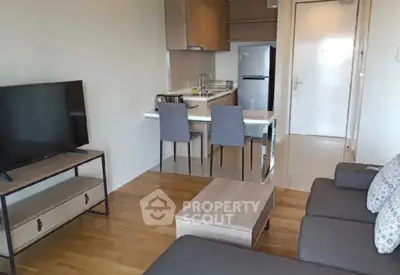 Modern open-plan living room with kitchen, featuring sleek furniture and wooden flooring.