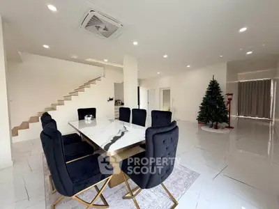Spacious modern dining room with elegant black chairs and marble table, featuring a festive Christmas tree.