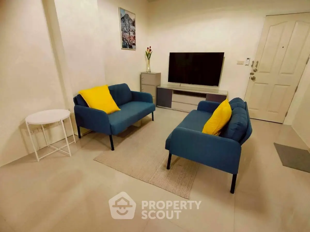 Cozy living room with modern blue sofas and a sleek TV setup, perfect for relaxation and entertainment.