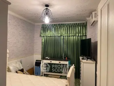 Cozy bedroom with stylish lighting and green curtains, featuring a TV and air conditioning for comfort.