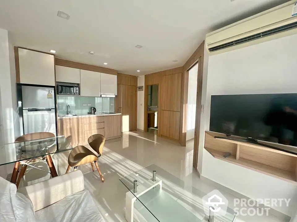 Modern living room with open kitchen, featuring sleek furniture and ample natural light.