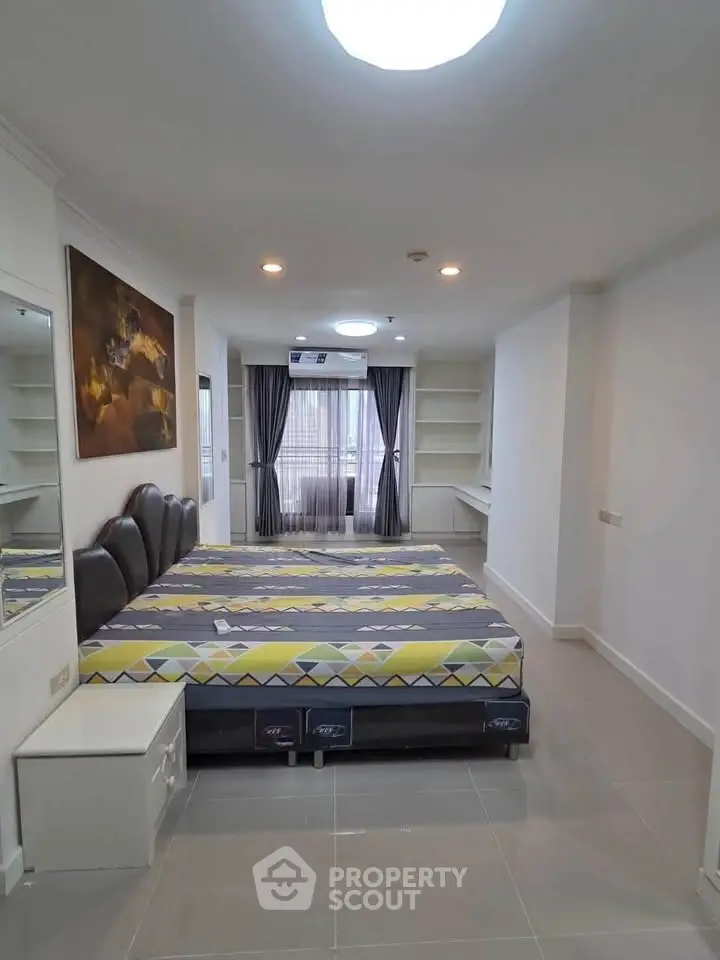 Spacious bedroom with modern decor and large window for natural light