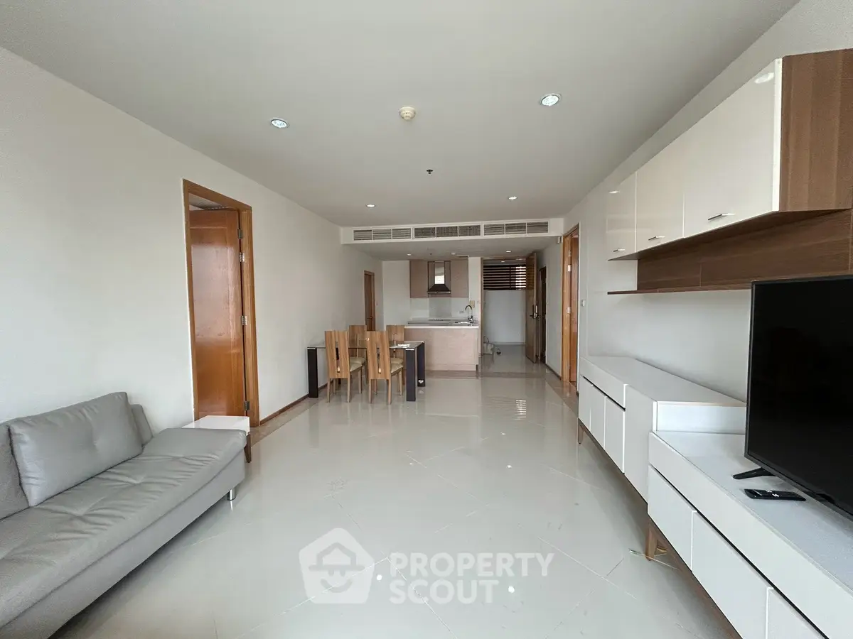 Spacious modern living room with sleek furniture and open kitchen layout in a contemporary apartment.
