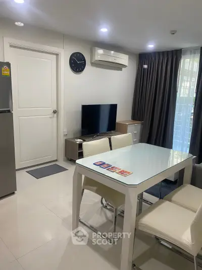 Modern living room with sleek furniture and natural light, featuring a wall-mounted TV and dining area.