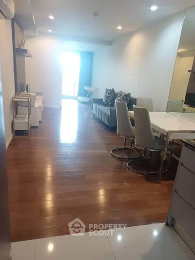 Spacious modern living room with wooden flooring and elegant dining area in a stylish apartment.