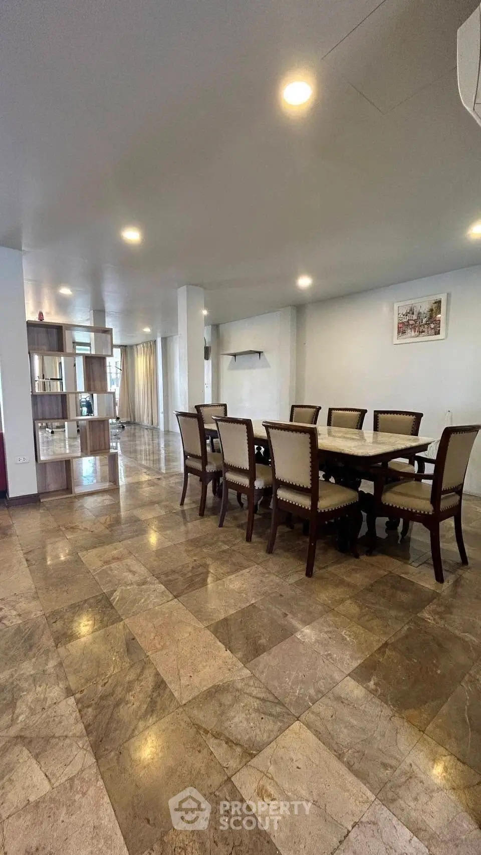 Spacious dining area with elegant furniture and marble flooring in a modern home.