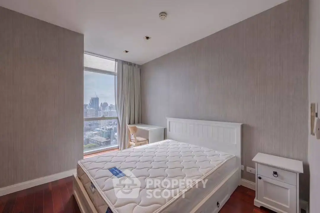 Spacious bedroom with city view, featuring a large window and modern furnishings.