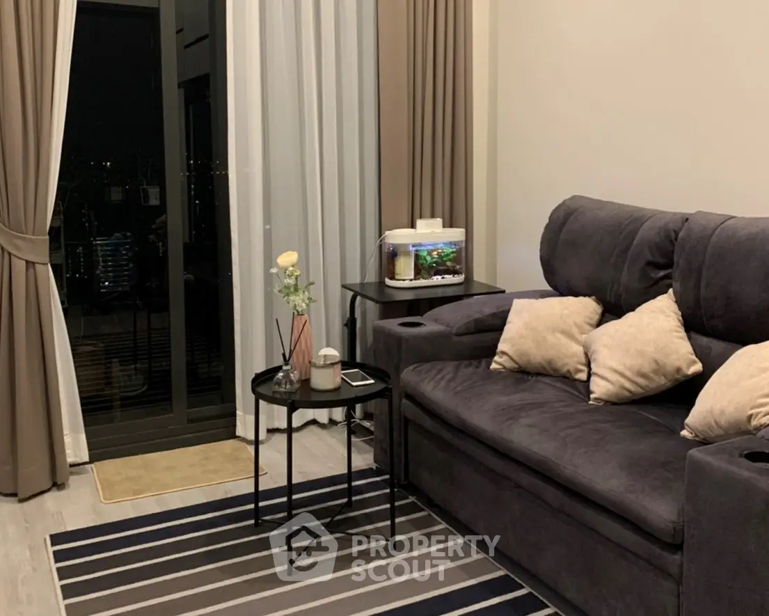 Cozy living room with plush sofa, stylish decor, and city view through large window.
