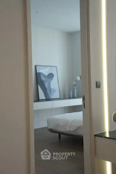 Modern bedroom with minimalist decor and abstract art on the wall, featuring a sleek bed and soft lighting.