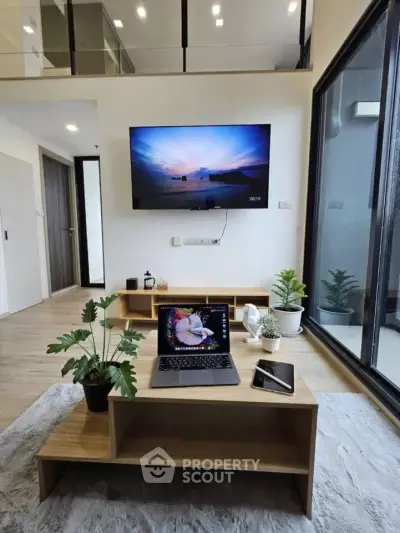 Modern living room with sleek design, large TV, and natural light from floor-to-ceiling windows.