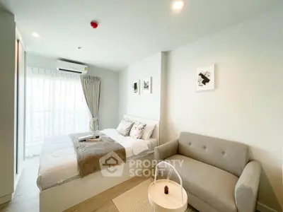 Modern bedroom with cozy sofa and natural light in stylish apartment.